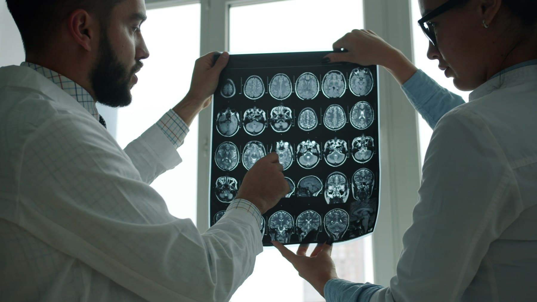 Two clinicians reviewing imaging together beside a window